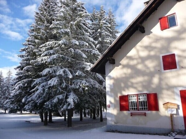 A snow-covered building with red shutters and a sign that reads "Le Cadran."