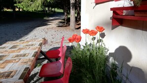 A patio with red chairs, a table, and a red wall with a window. - Rifugio La Capanna (Claviere)