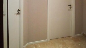 A hallway with two white doors, beige walls, and a tiled floor. - Home La Kore (Agrigento)