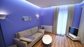 A modern living room with a sofa, a coffee table, a flat-screen TV, and a window with curtains. - Haus am Meer (Wunstorf)