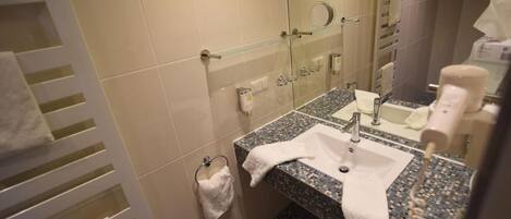Un baño con lavamanos, espejo, toallero y secador de pelo.