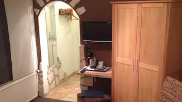 Quarto de hotel com uma cama, uma escrivaninha com cadeira, televisão e guarda-roupa.
