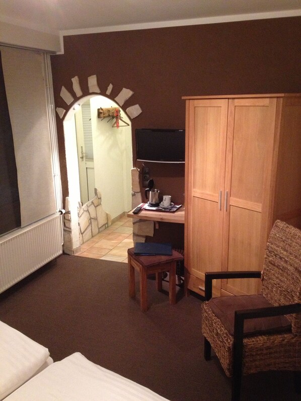 A hotel room with a bed, a desk with a chair, a television, and a wardrobe.