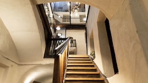 A wooden staircase with a curved ceiling and a view of a balcony with a modern light fixture.