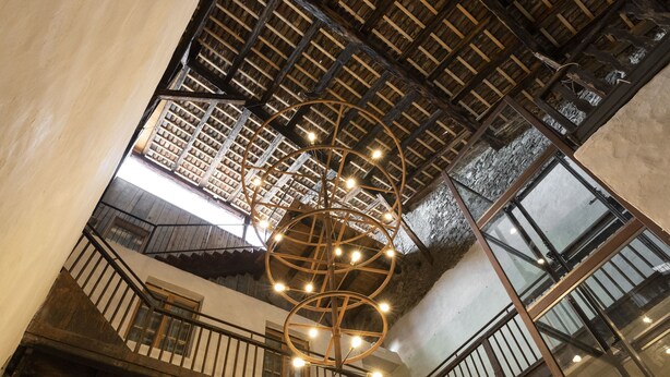 A multi-level interior with a wooden ceiling, a spiral light fixture, and a staircase.