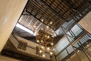 Un intérieur à plusieurs niveaux, doté d’un plafond en bois, d’un luminaire en forme de spirale et d’un escalier.
