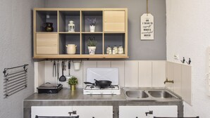 A compact kitchen with a built-in stove, two sinks, and a wooden cabinet above the counter. - Holiday home Klarisa (Novalja)