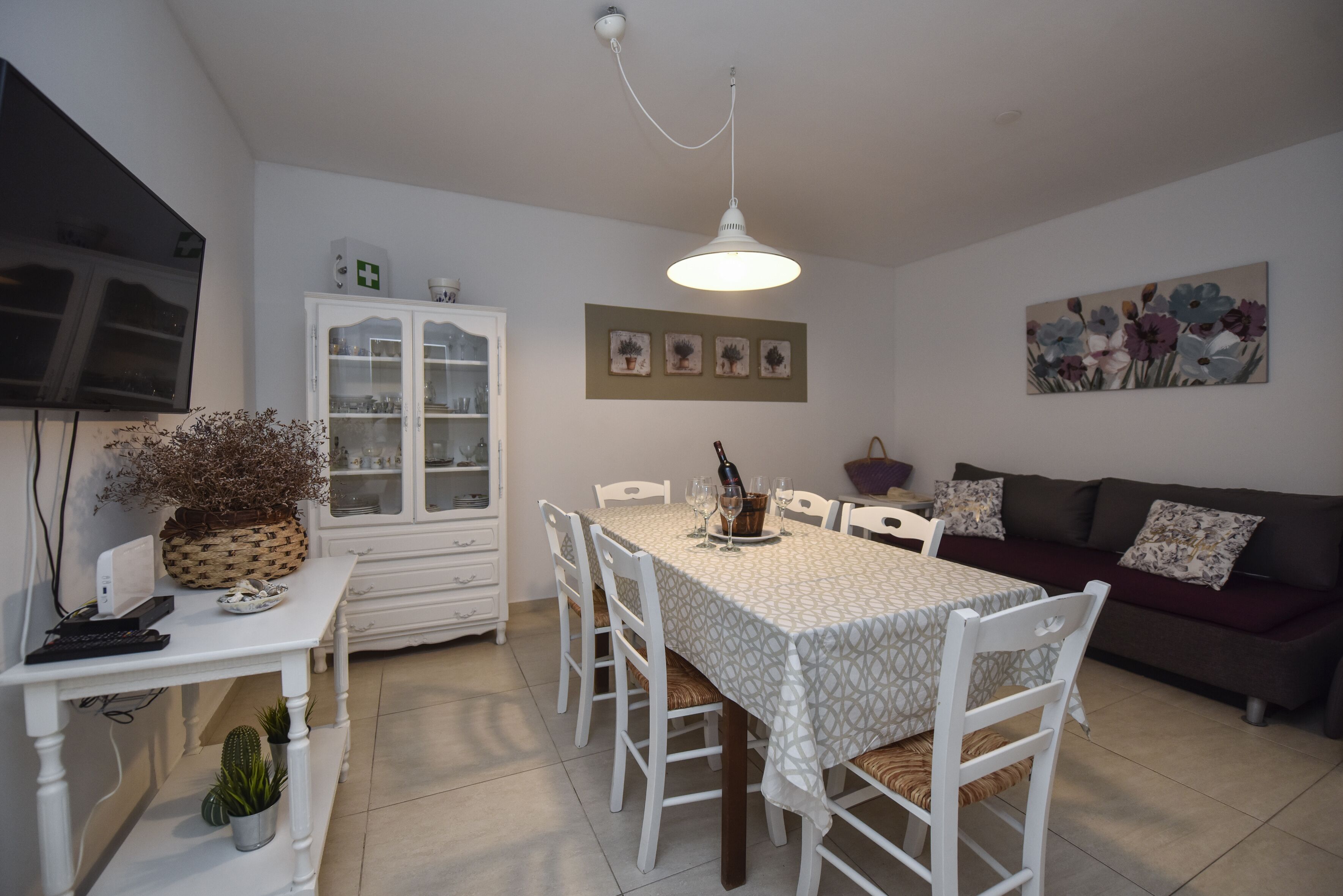 A dining area with a table, chairs, a cabinet, and a television.