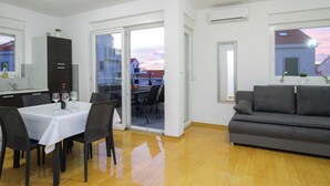 Una sala moderna con comedor, un sofá y una puerta corrediza de vidrio que da a un balcón.