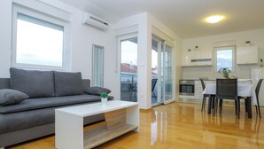 Una sala de estar moderna con un sofá gris, una mesa de centro blanca y un comedor con mesa y sillas.