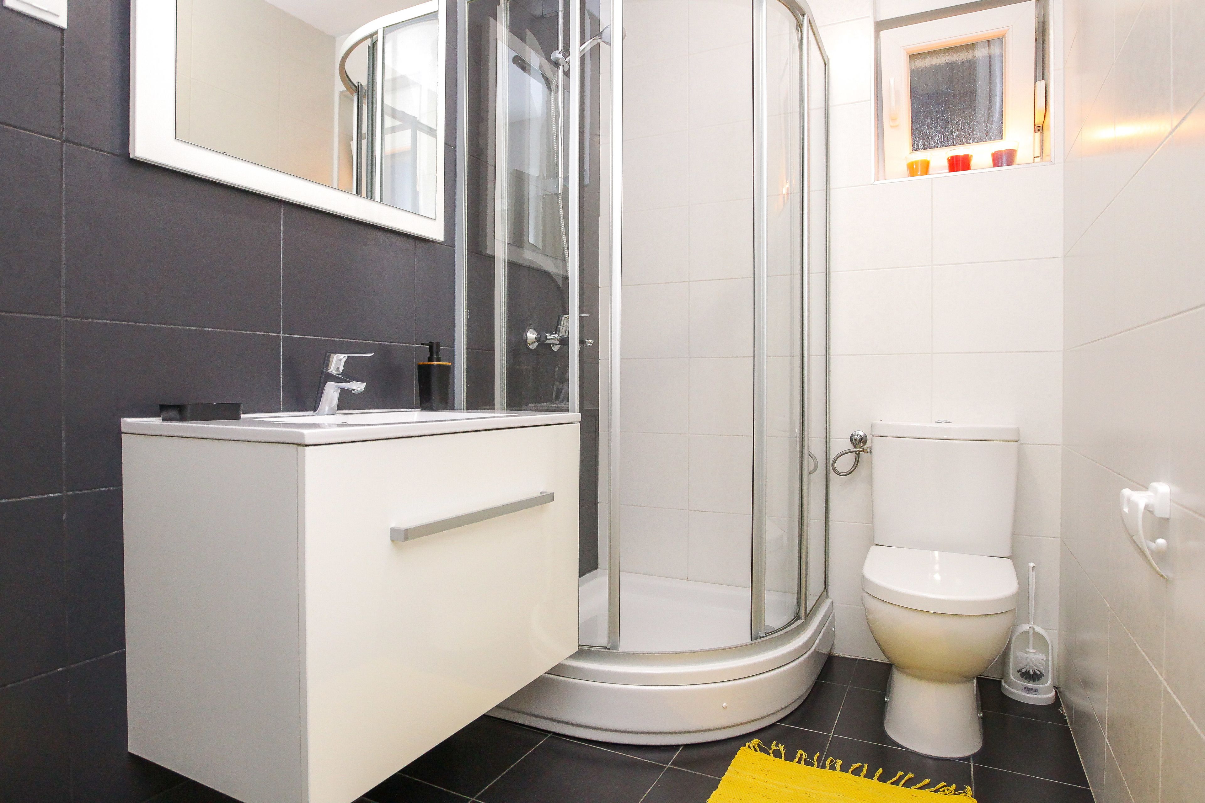 A bathroom with a glass-enclosed shower, a toilet, and a sink with a cabinet.