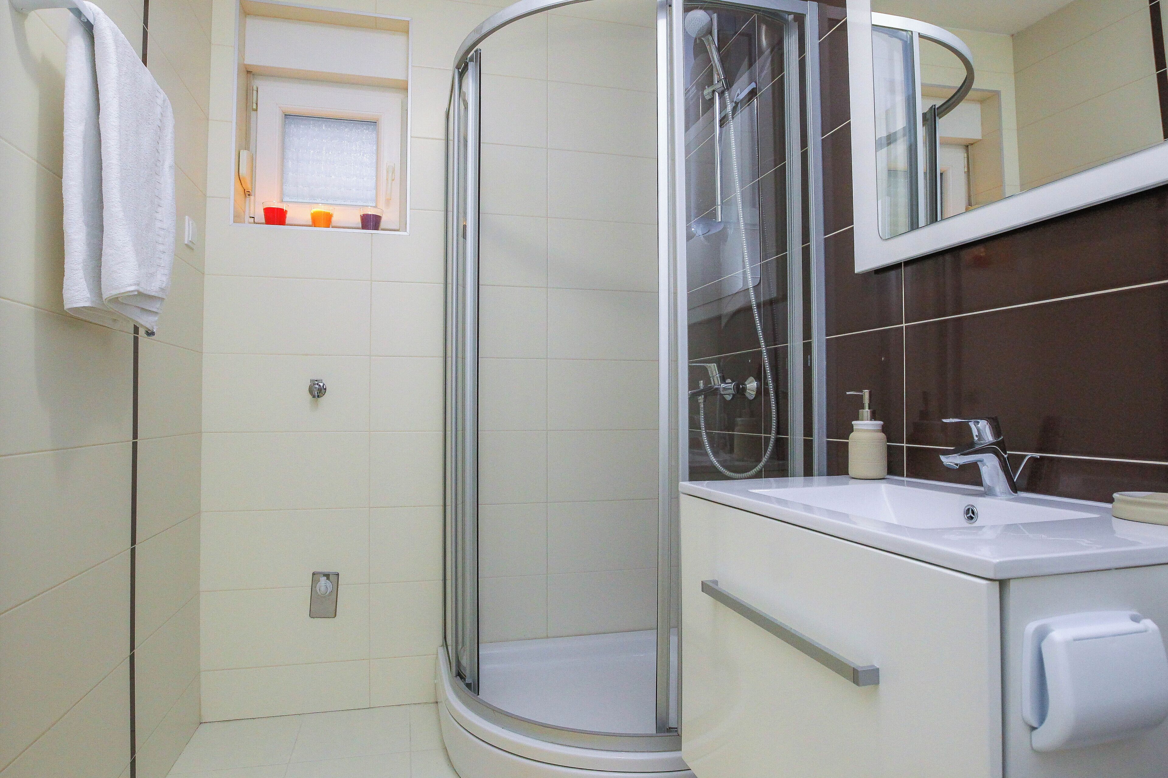 A modern bathroom with a glass-enclosed shower, a sink, and a mirror.