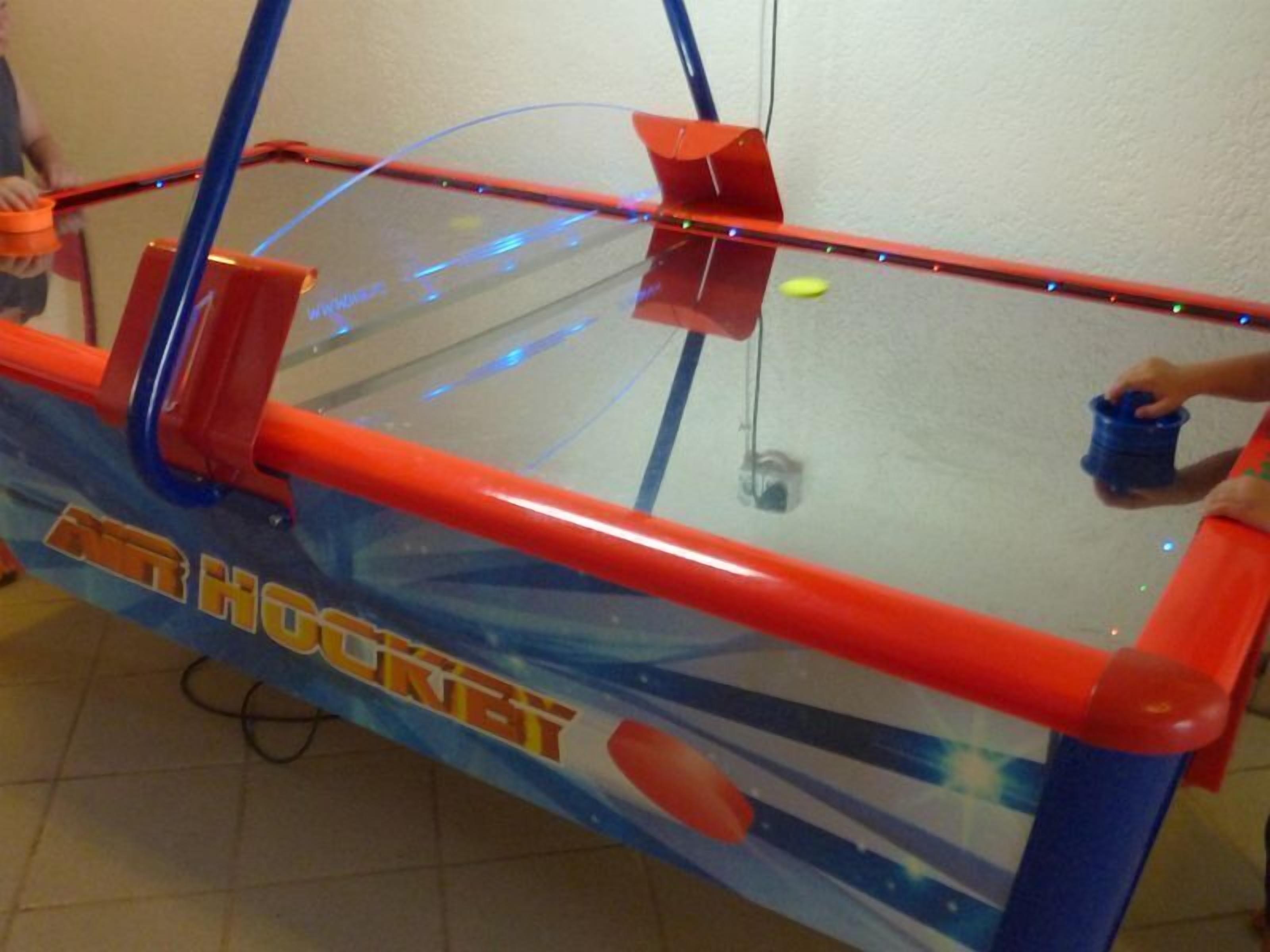 Una pequeña pista de hockey cubierta con una cubierta de vidrio y estructura roja y azul.