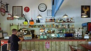 A bar with wooden counters, shelves of bottles, and a clock on the wall.