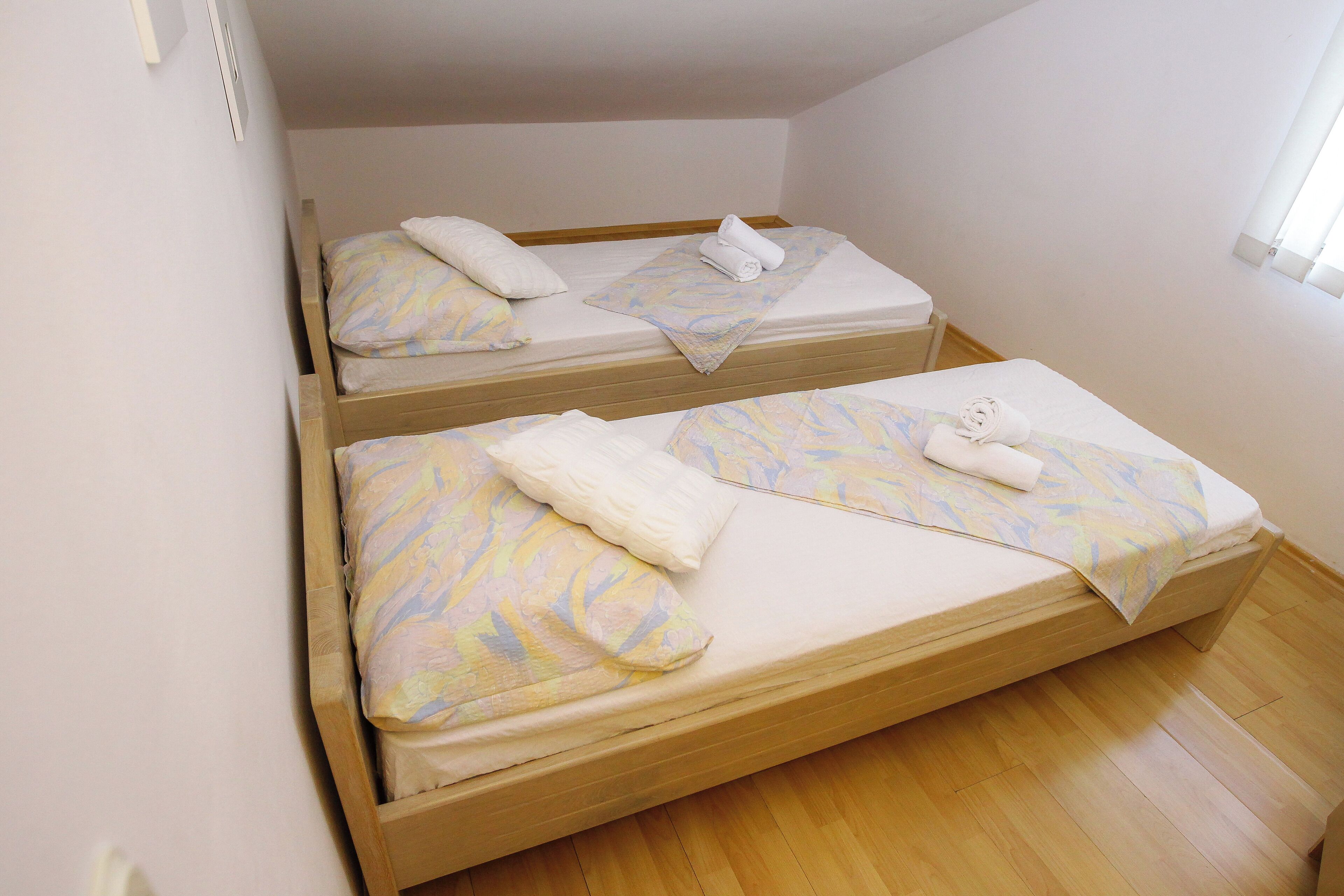Une chambre avec deux lits superposés en bois, chacun étant équipé d’un matelas et d’oreillers.