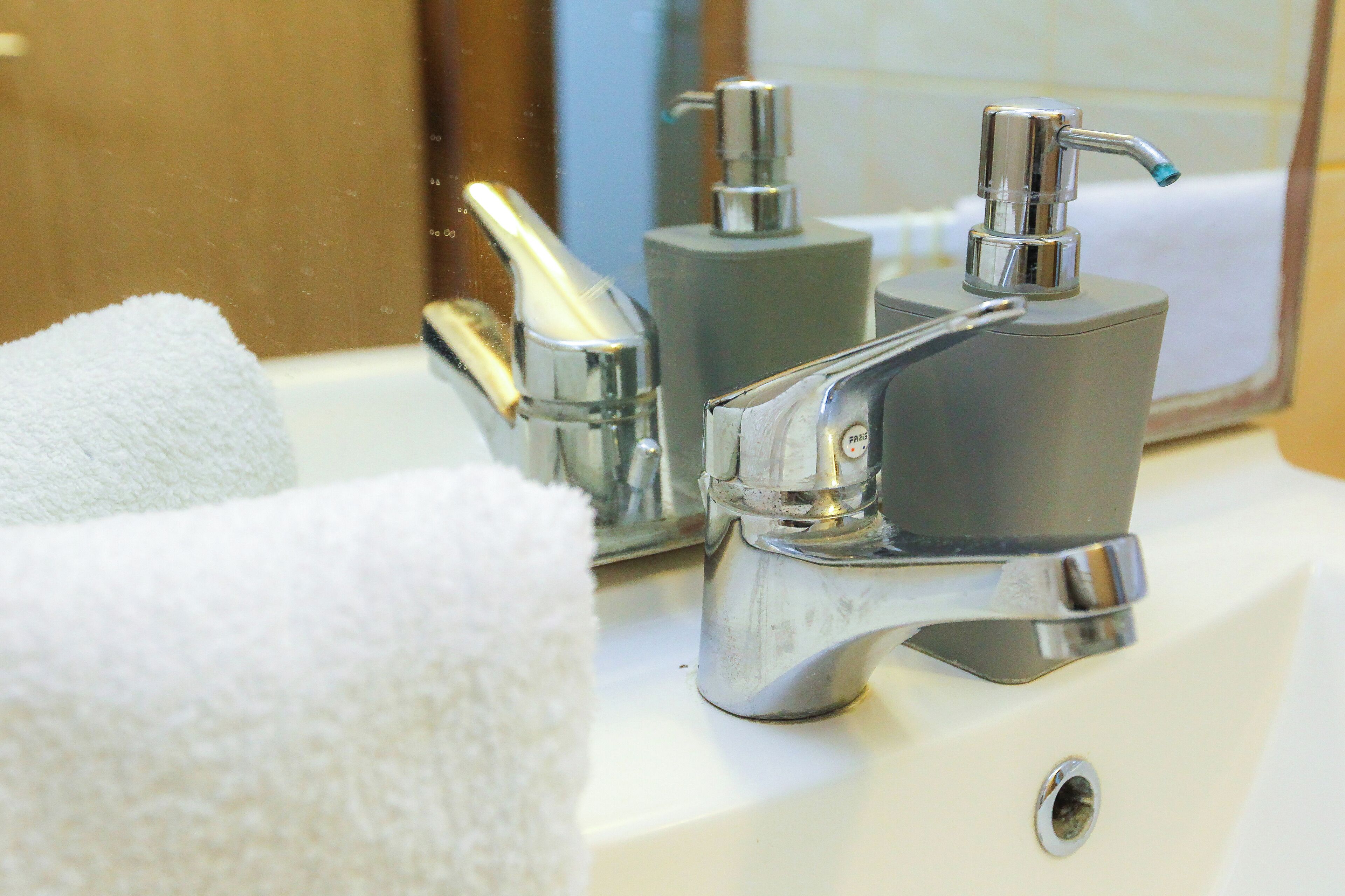 Un lavabo de salle de bain avec un robinet chromé, un distributeur de savon et une serviette.