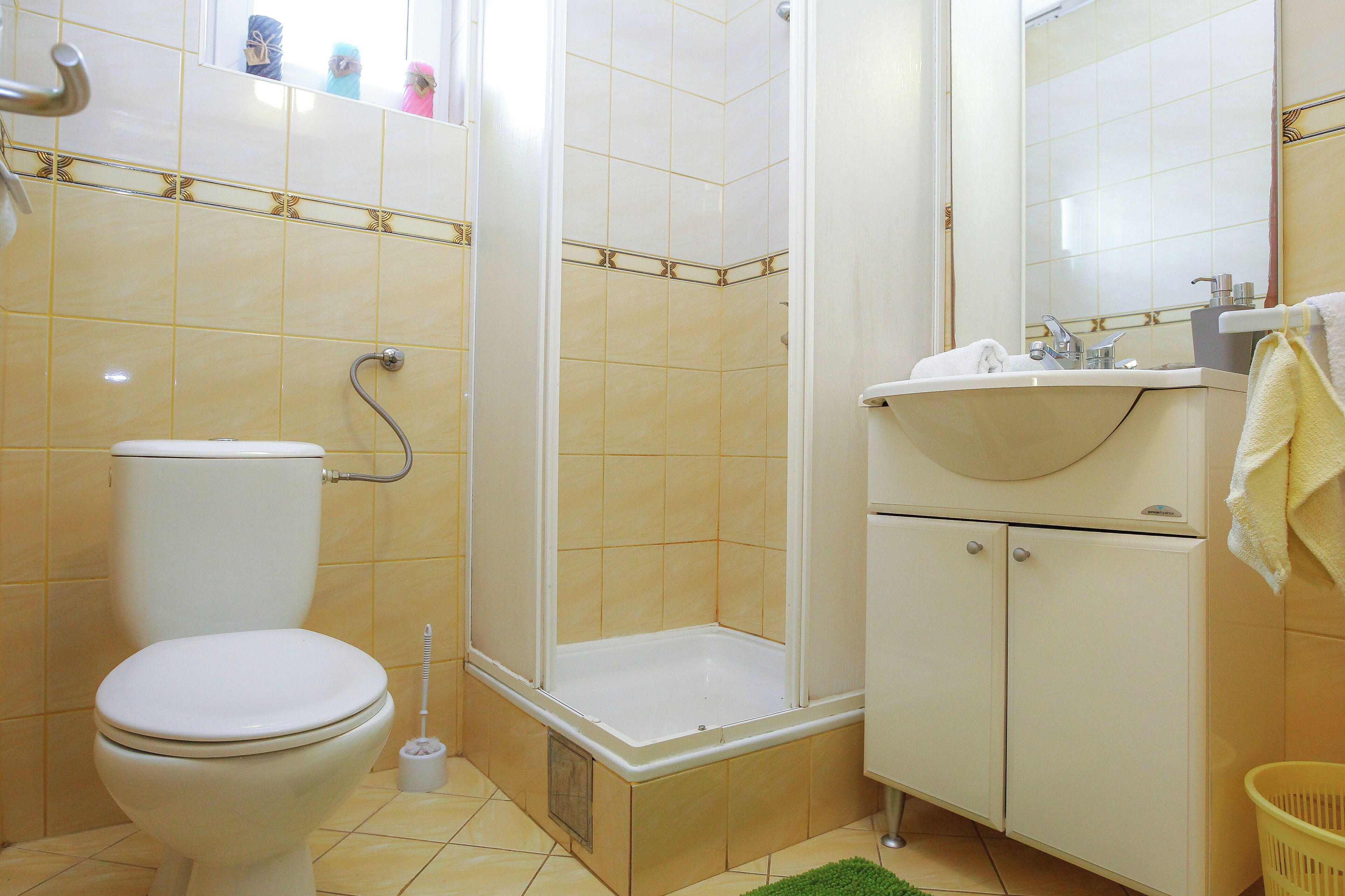 A bathroom with a toilet, shower, sink, and cabinets.