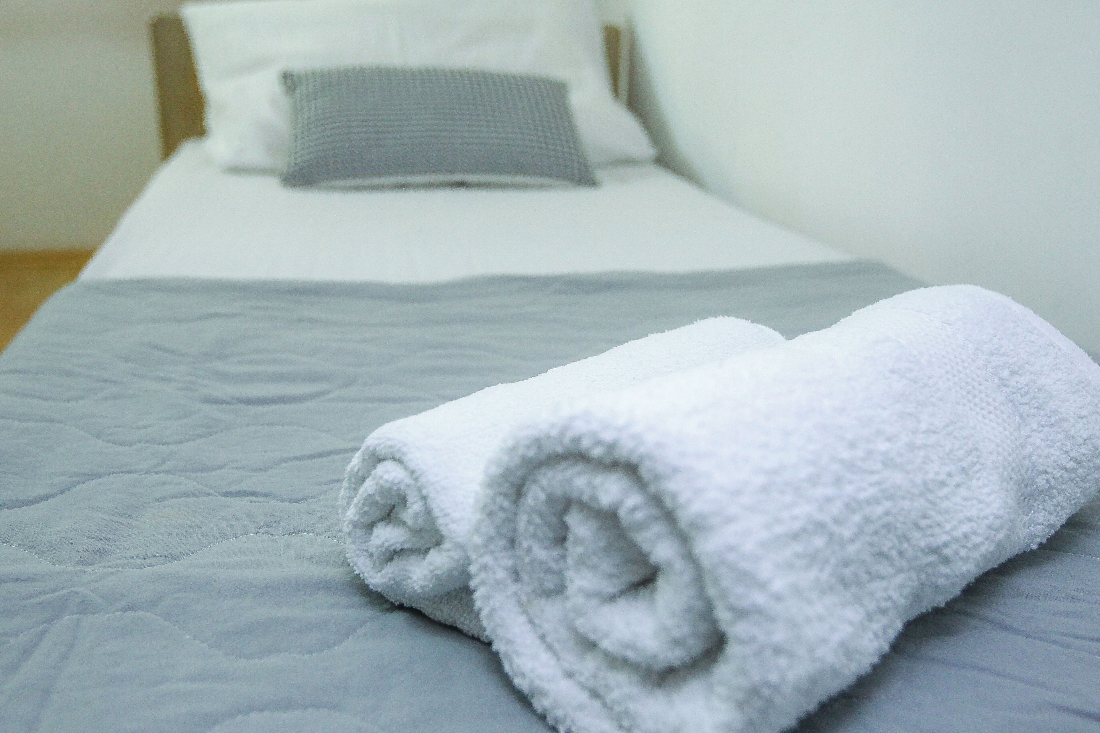 Una cama bien hecha con una toalla blanca enrollada al pie.