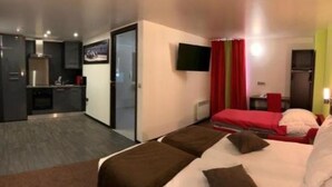 Een hotelkamer met een bed, een klein bureau, een televisie en een kitchenette.