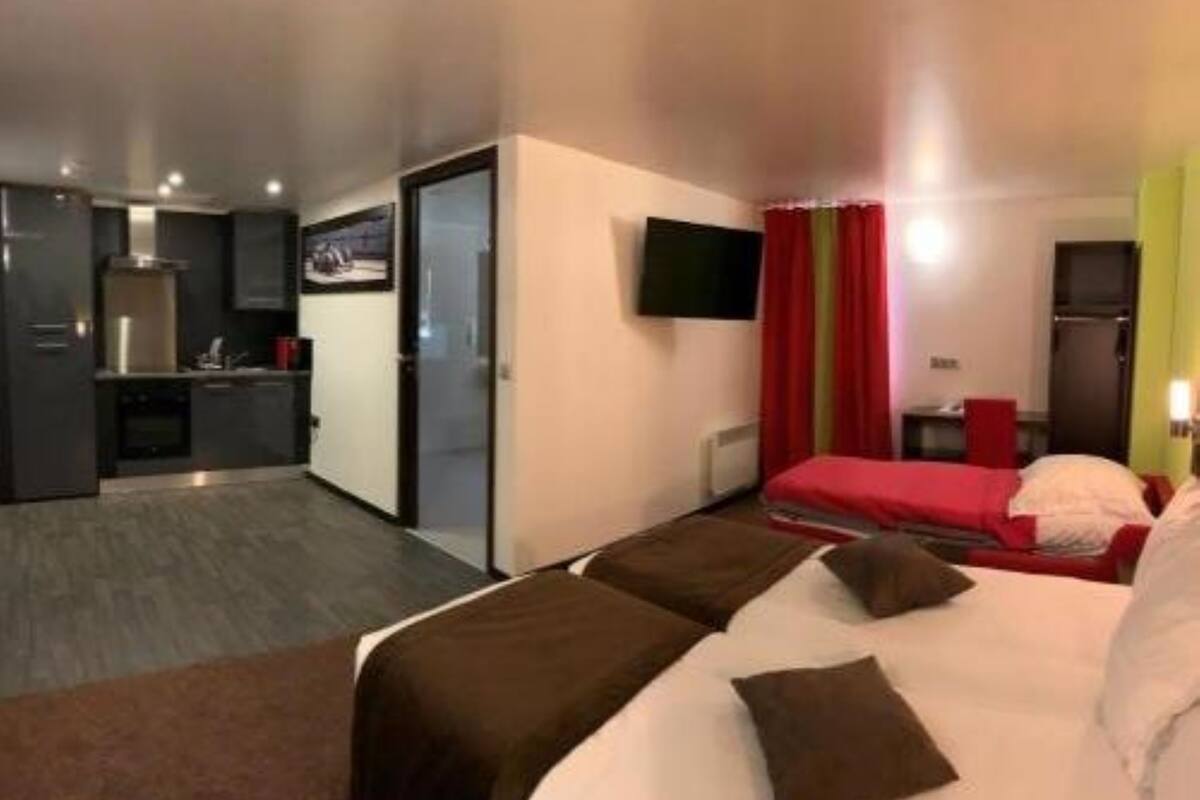 A hotel room with a bed, a small desk, a TV, and a kitchenette.