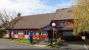 Een rood gebouw met een pannendak, een overdekte ingang en een bord waarop 