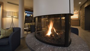 A modern living room with a stone fireplace, a comfortable sofa, and a lamp. - Sonnenhof Hotel & Restaurant (Lautenbach)