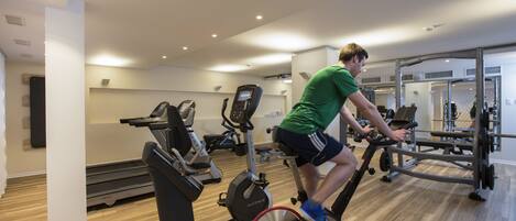 A gym with cardio equipment, weight machines, and mirrors.