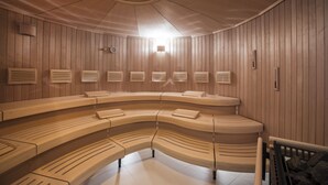 A sauna with wooden benches arranged in a semi-circular layout, a central light fixture, and wall-mounted ventilation panels. - Sonnenhof Hotel & Restaurant (Lautenbach)