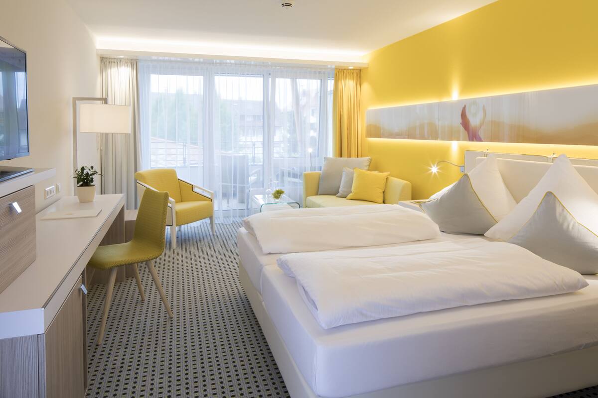 Ein Hotelzimmer mit Bett, Schreibtisch, Stuhl und Fernseher.