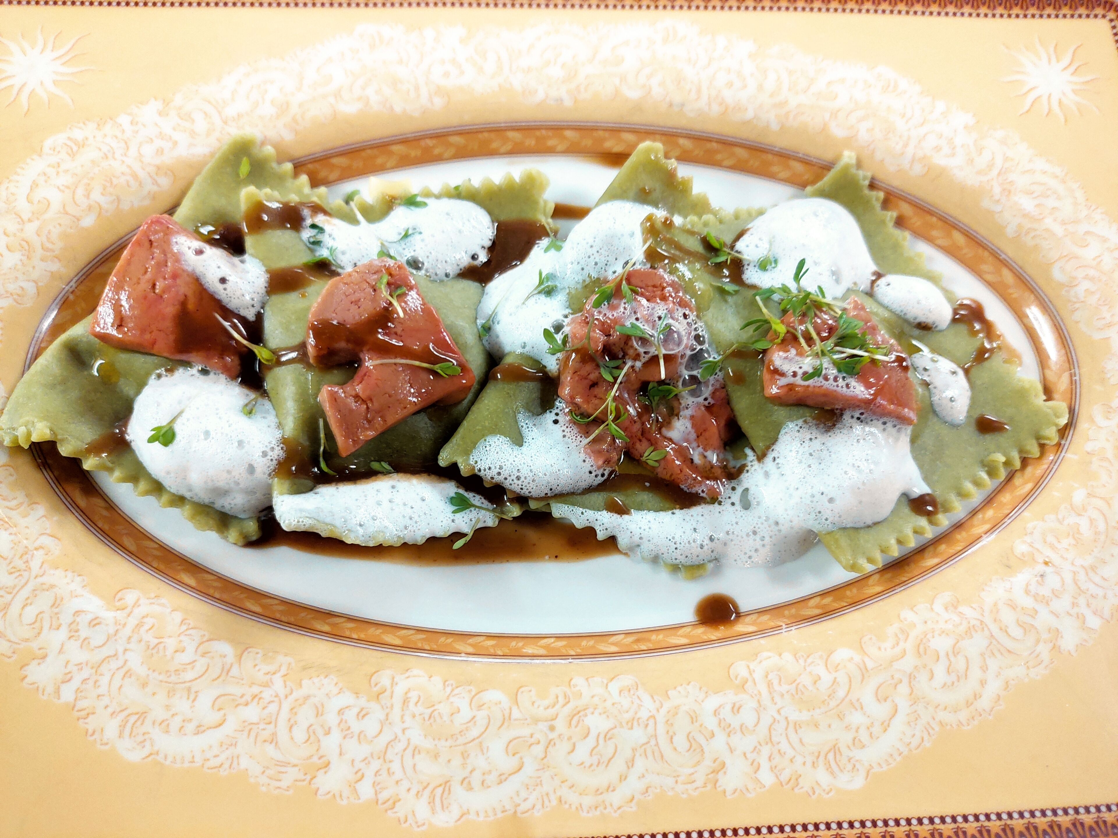 Um prato de ravioli com molho cremoso e guarnecido com ervas.