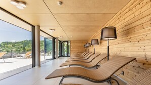 A modern waiting area with wooden walls, large windows, and several lounge chairs. - Sonnenhof Hotel & Restaurant (Lautenbach)