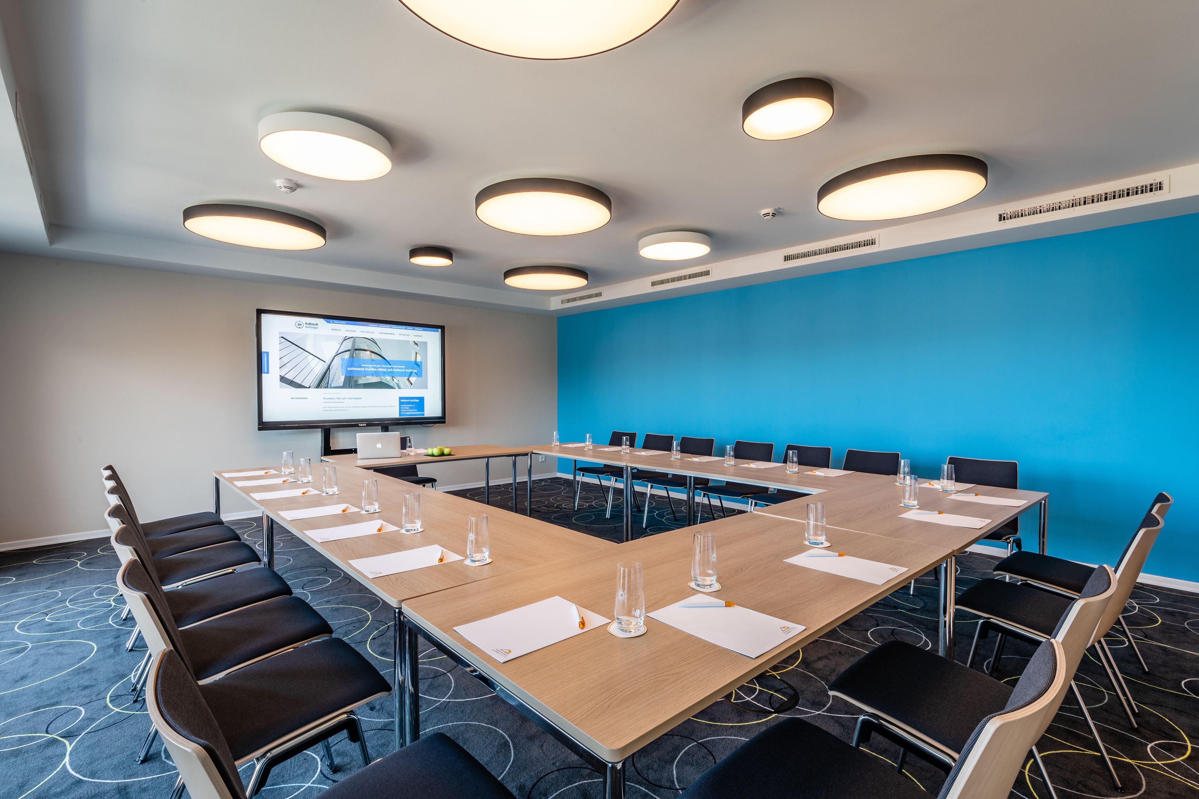 A conference room with a long table, chairs, and a projector screen.