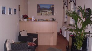 Een zithoek met een bank, een tafeltje, een plant en een schilderij aan de muur.