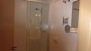 Een badkamer met een douchecabine van glas, een toilet en een wastafel.