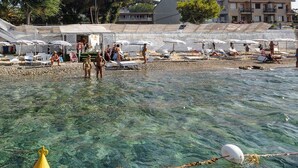 A beach with clear water, umbrellas, and people. - Il Ritrovo di Ulisse Bed & Breakfast (Villa San Giovanni)