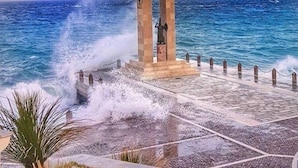 A stone monument with inscriptions, located by the sea with waves crashing onto a paved walkway. - Il Ritrovo di Ulisse Bed & Breakfast (Villa San Giovanni)