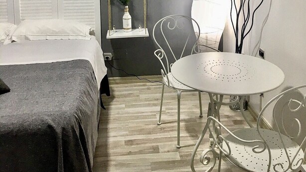 A bedroom with a bed, bedside table, chair, and a small table with a lamp. - Il Ritrovo di Ulisse Bed & Breakfast (Villa San Giovanni)