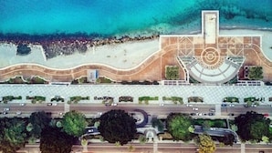 An aerial view of a coastal building with a curved roof, a central tower, and a beach in the background. - Il Ritrovo di Ulisse Bed & Breakfast (Villa San Giovanni)