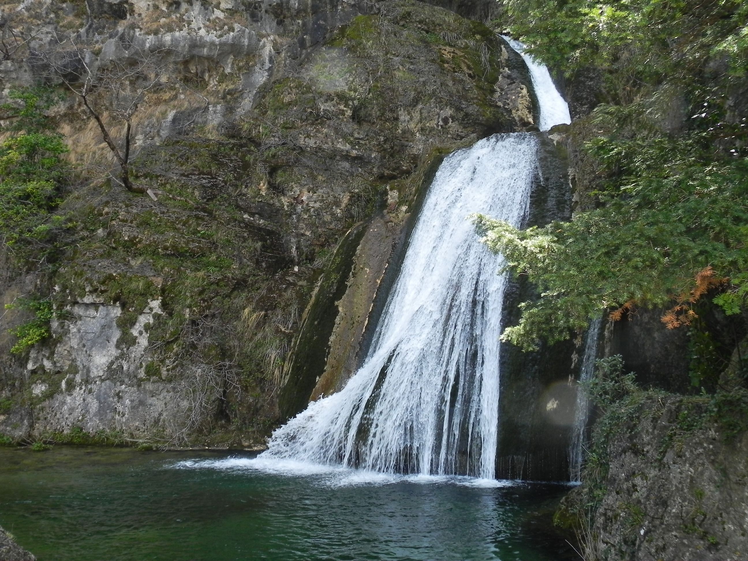 Un cascada que desemboiga sobre una roca cap a una bassa cristal·lina.