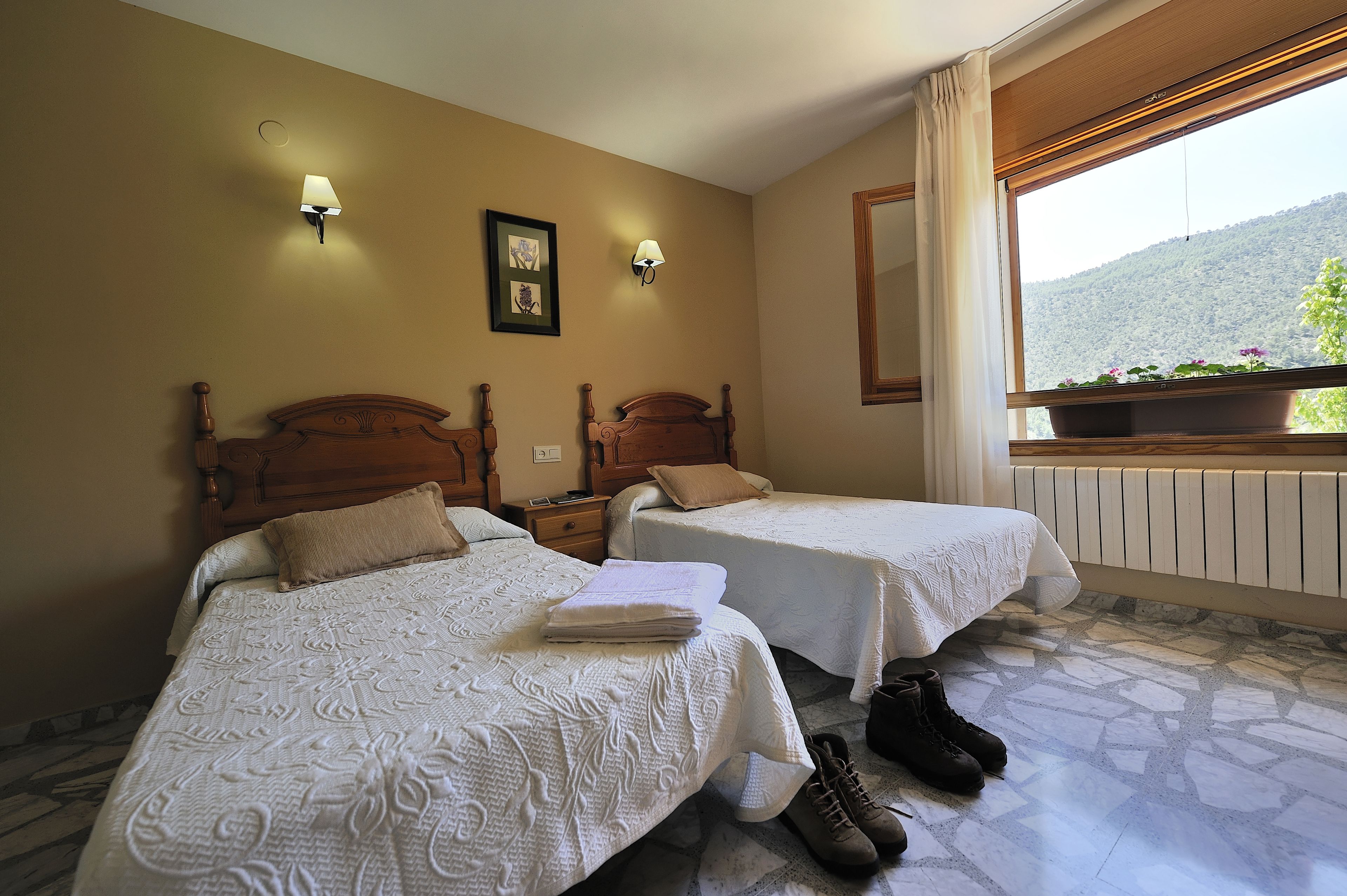 Una habitación de hotel con dos camas, un ventanal con vistas a la montaña y un radiador.
