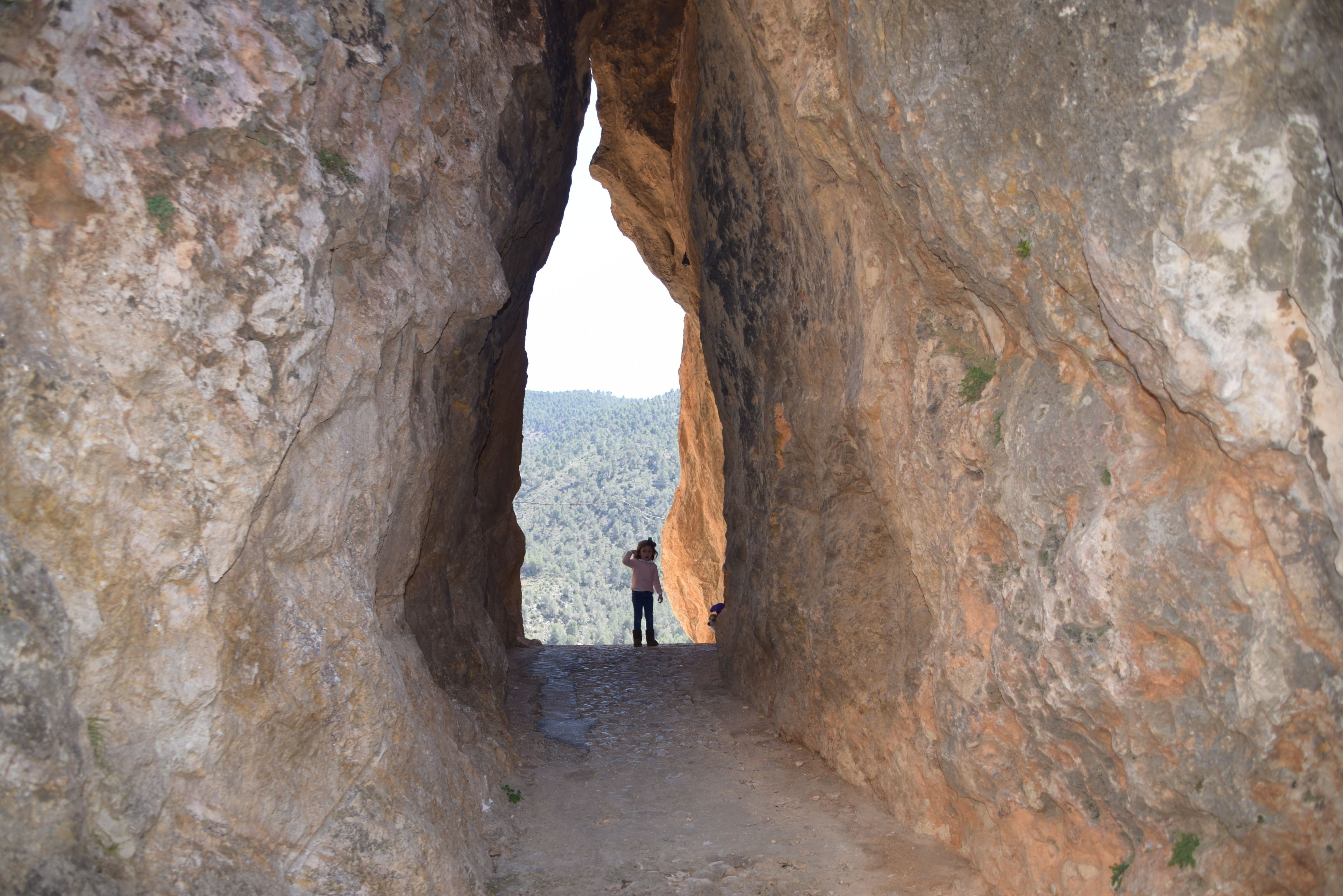 A narrow passageway between large rock formations with a person standing at the end.