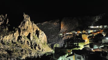 A mountainous village at night with illuminated buildings.