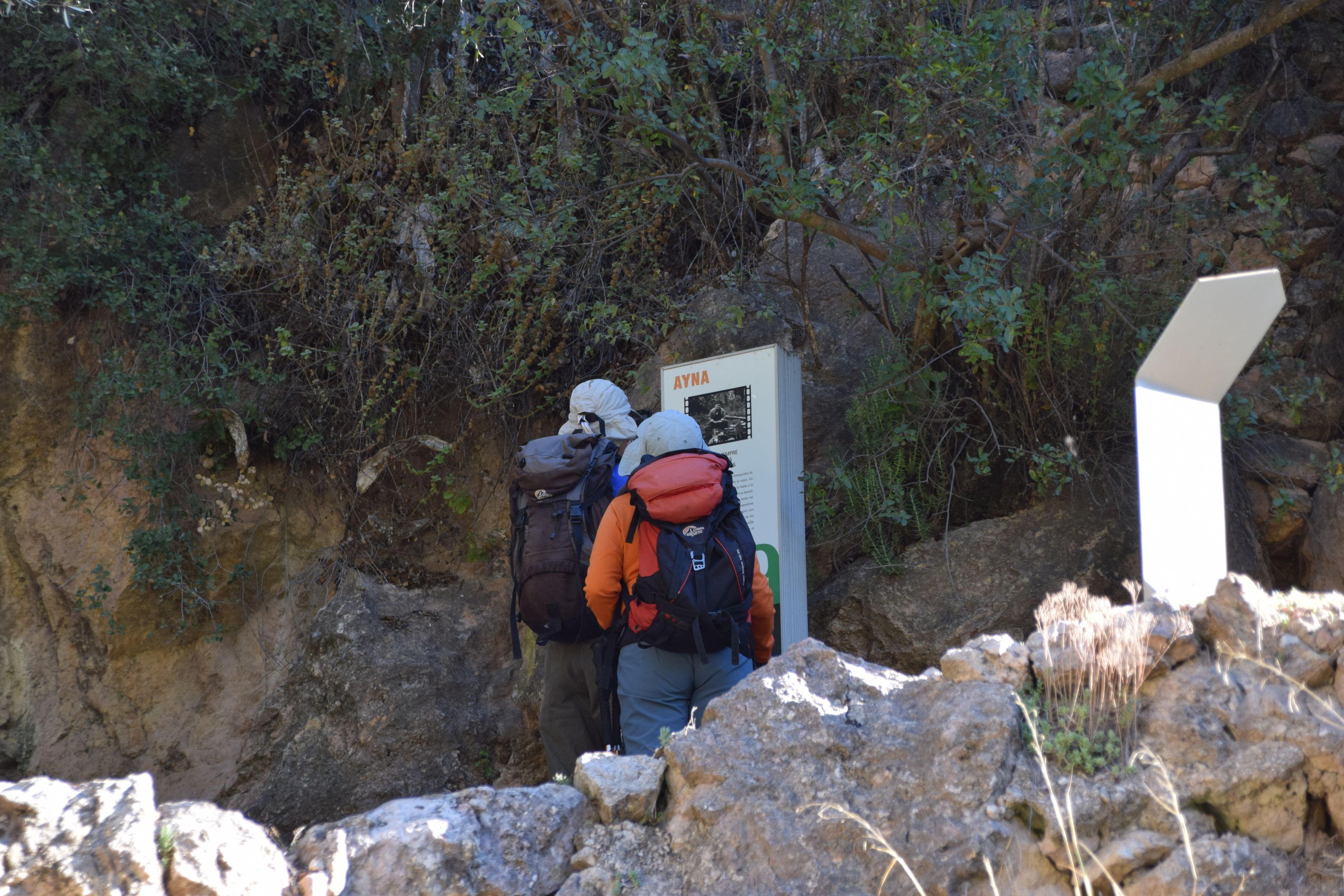 Gerölliges Gelände mit einem Hinweisschild und einer Person mit Rucksack.