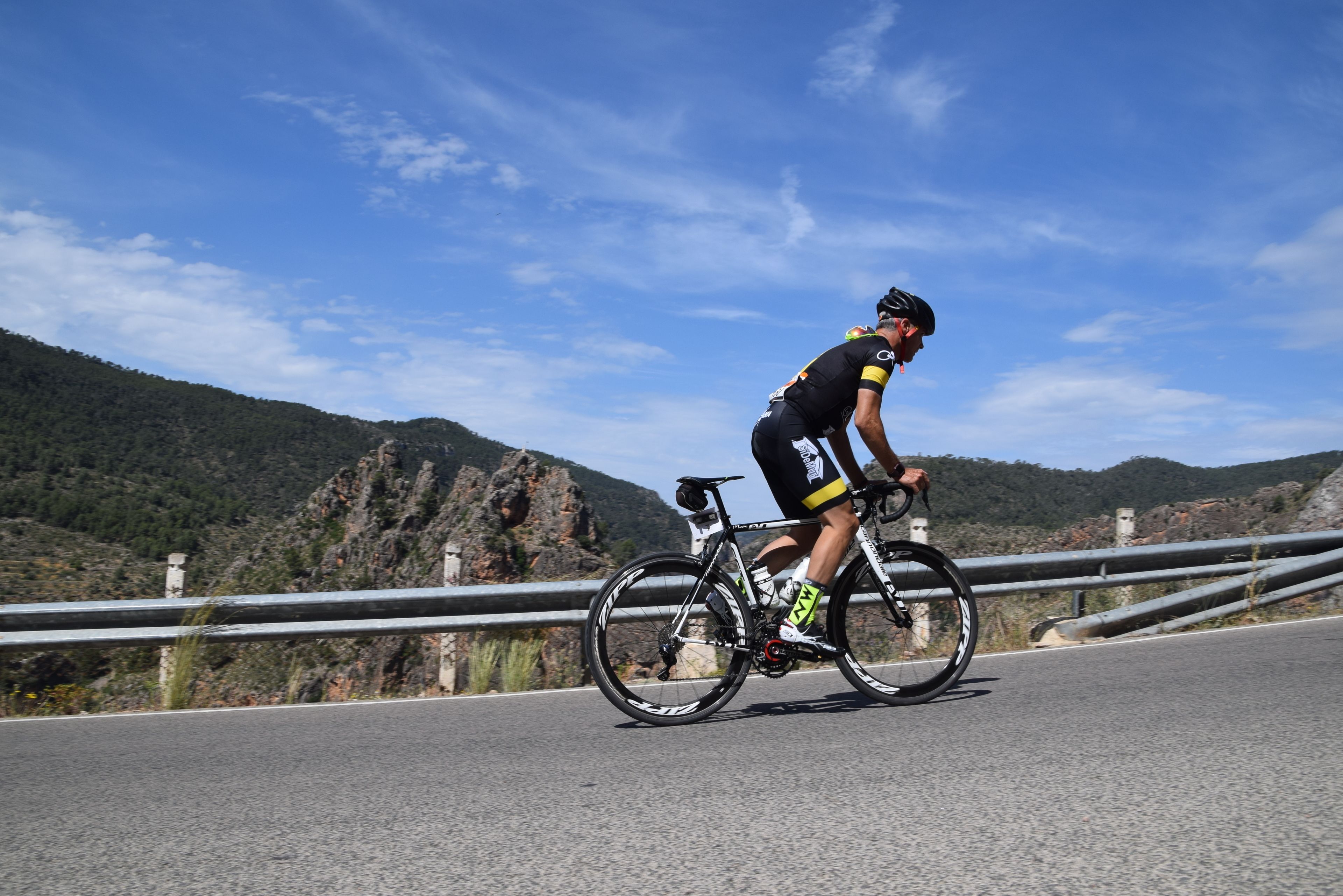 A cyclist on a road with a mountainous backdrop.