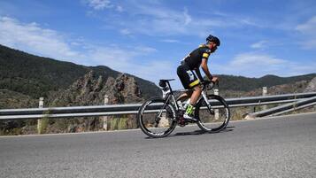 A cyclist on a road with a mountainous backdrop.