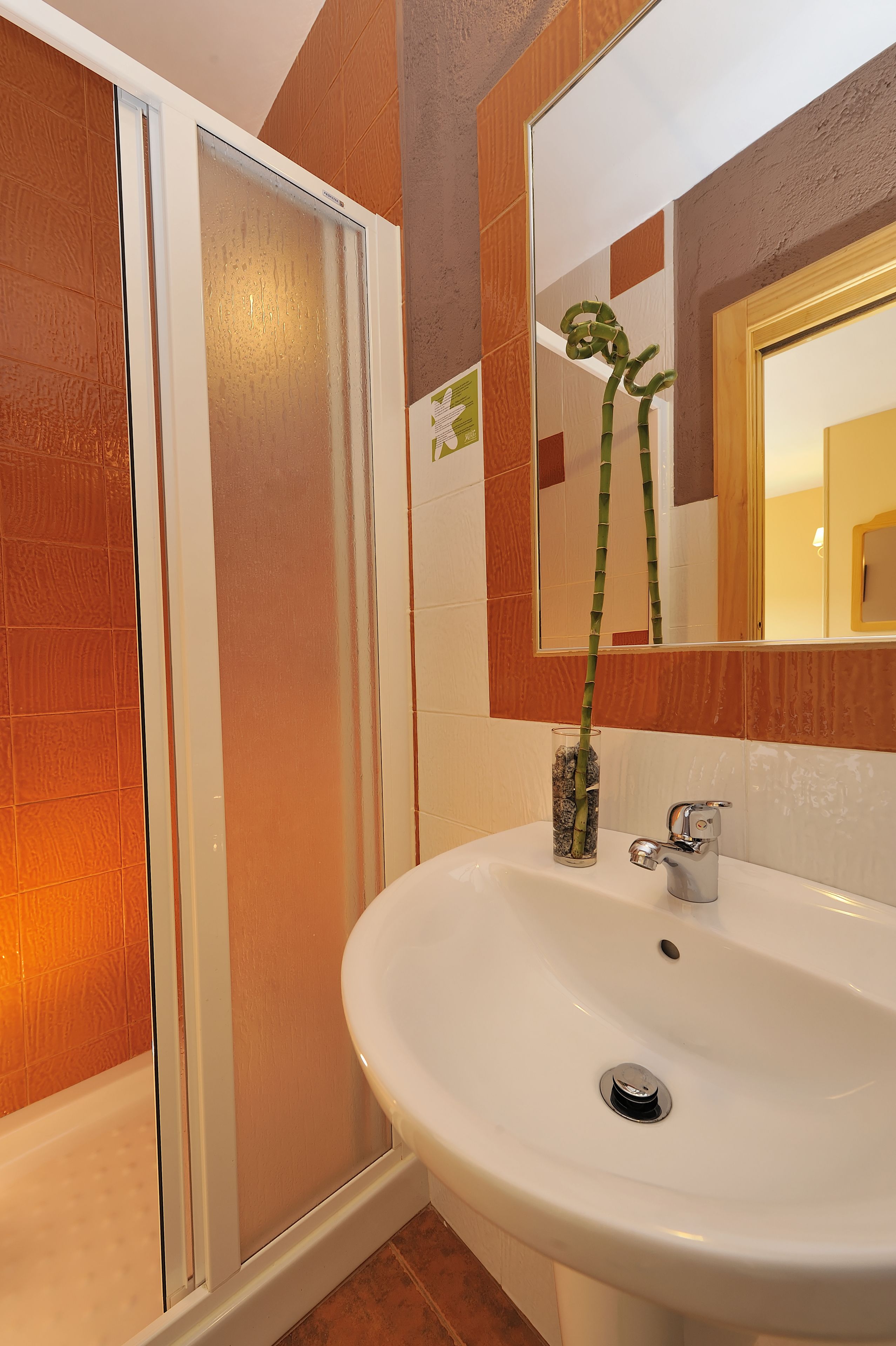 A bathroom with a glass shower enclosure, a white sink, and a mirror above the sink.