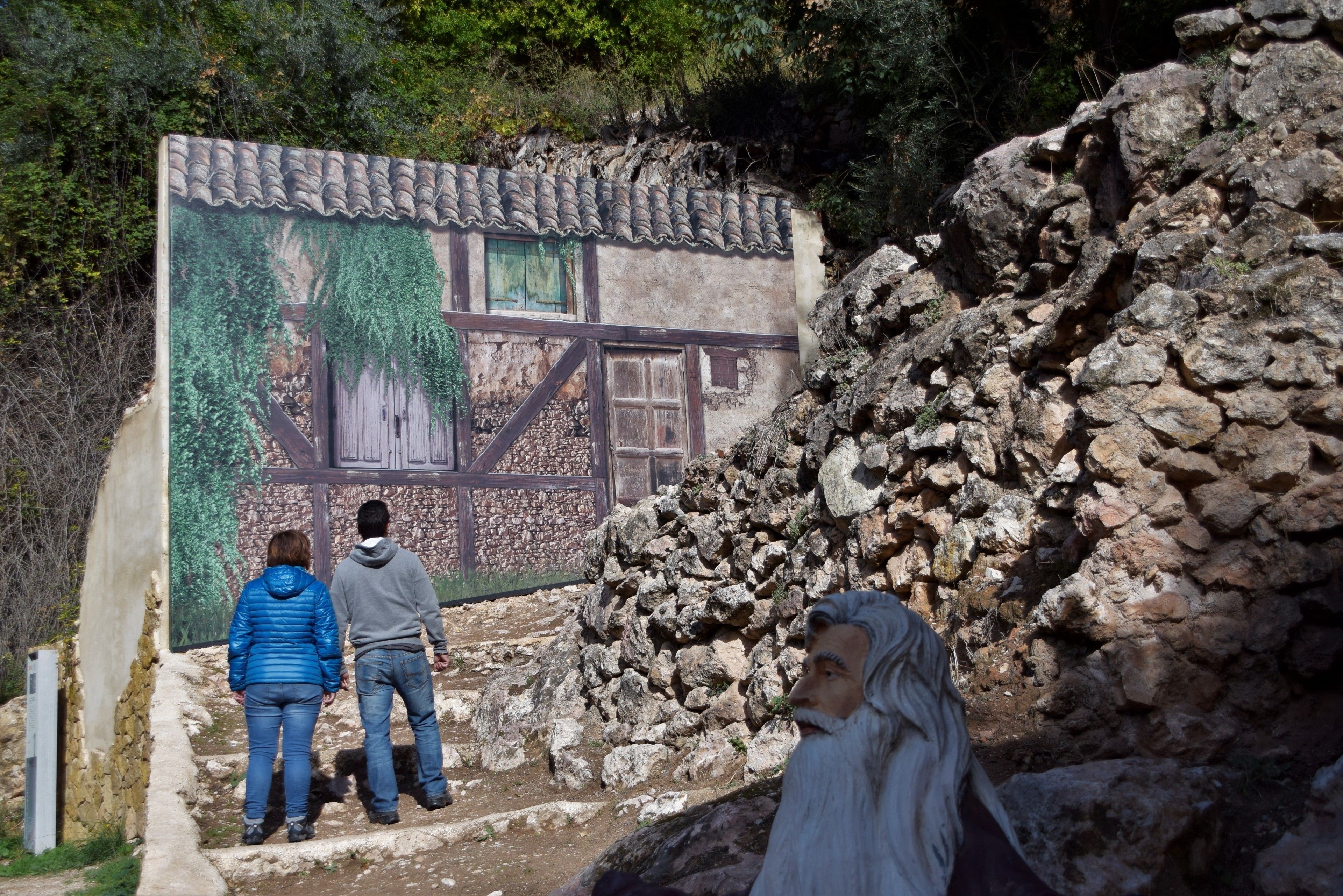Un muro de piedra con un edificio rústico al fondo.