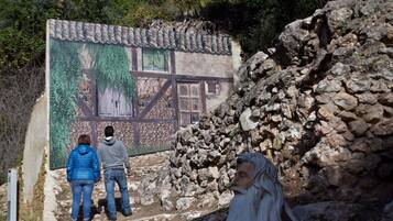 Un muro de piedra con un edificio rústico al fondo.
