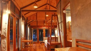 A wooden interior with a bed, a table, and a bench.