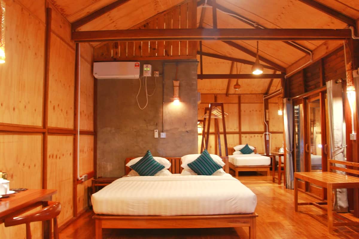 A wooden cabin room with a bed, a desk, and a chair.